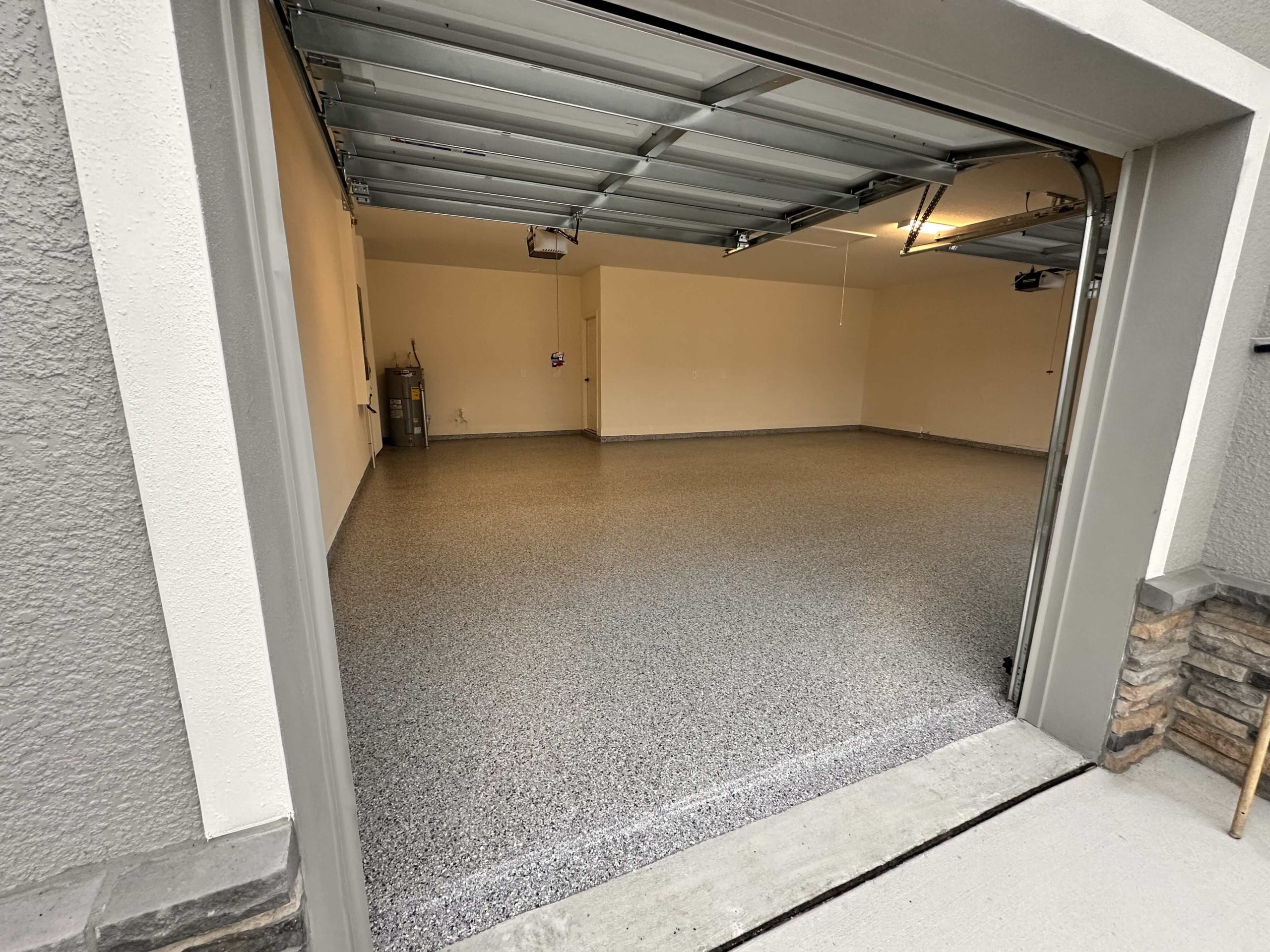 Open view of two-car garage with new epoxy flooring and exterior threshold.