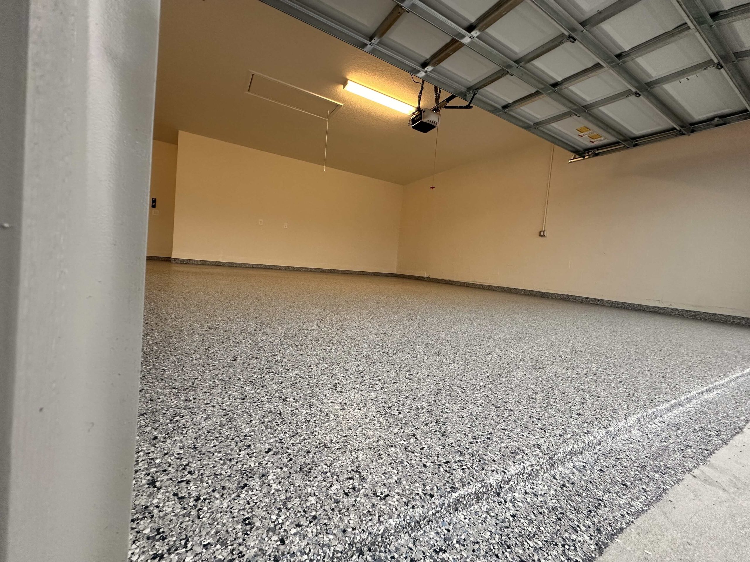 Low-angle view of epoxy garage floor showing smooth flake texture and gloss.