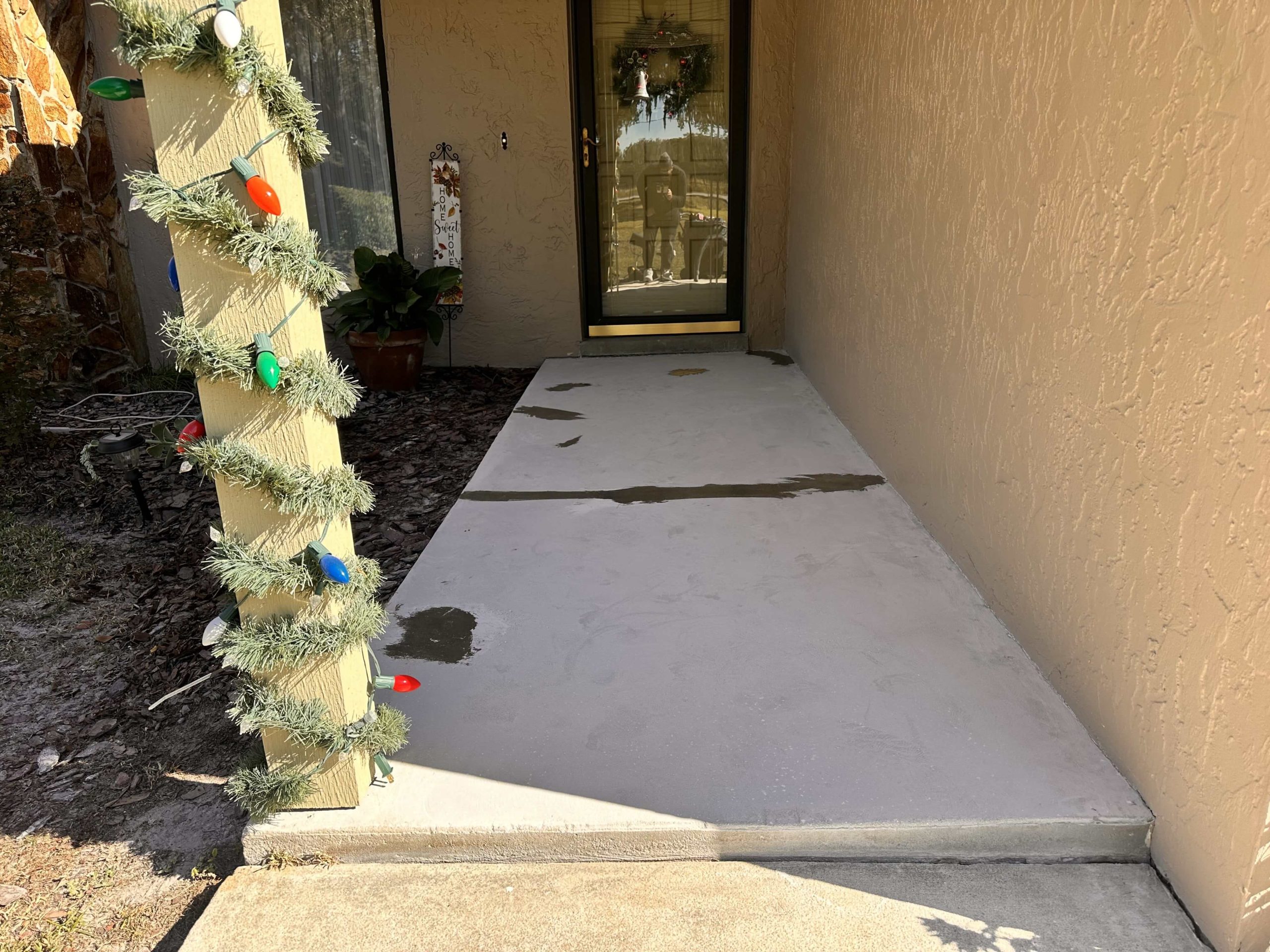Concrete porch with patches and visible repair marks before epoxy application